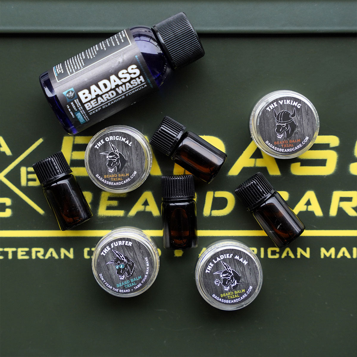 Trial-size Beard Wash, beard oils and balm tins arranged on a Badass Beard Care box